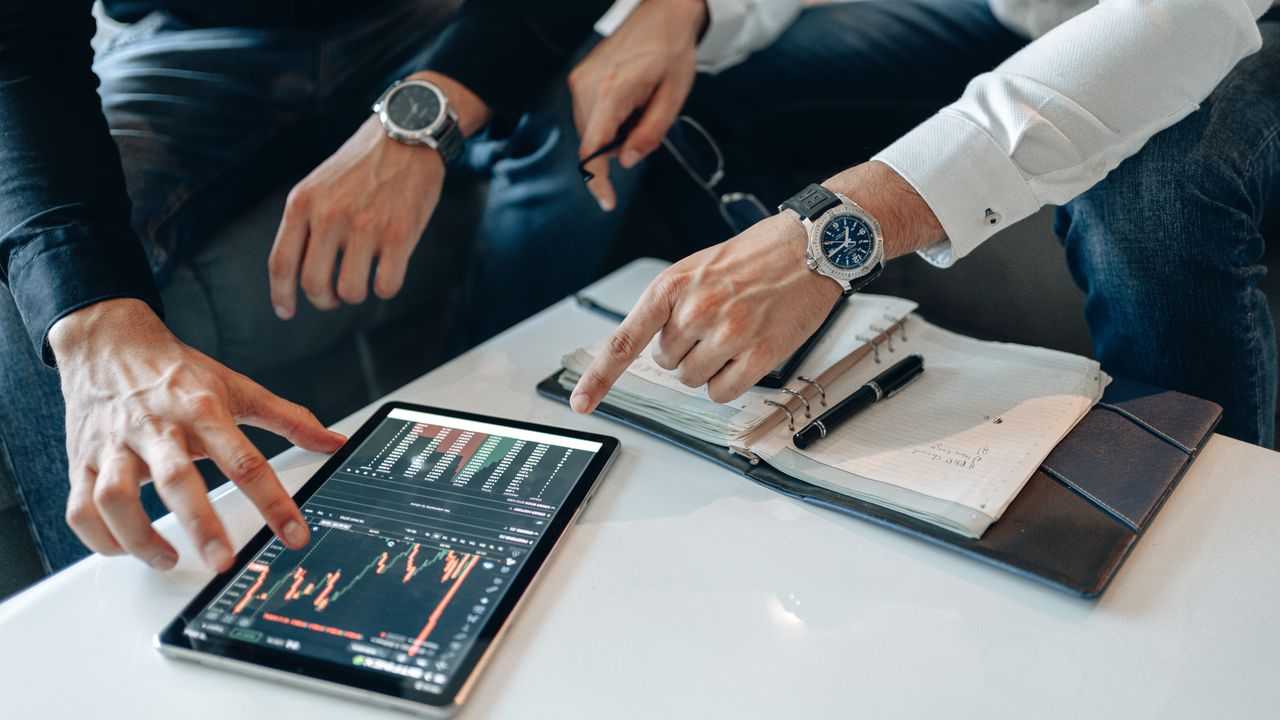 Mastering the First Impression: Your intriguing post title goes here Close-up of professionals discussing stock charts on a tablet with notes and pens on a table.